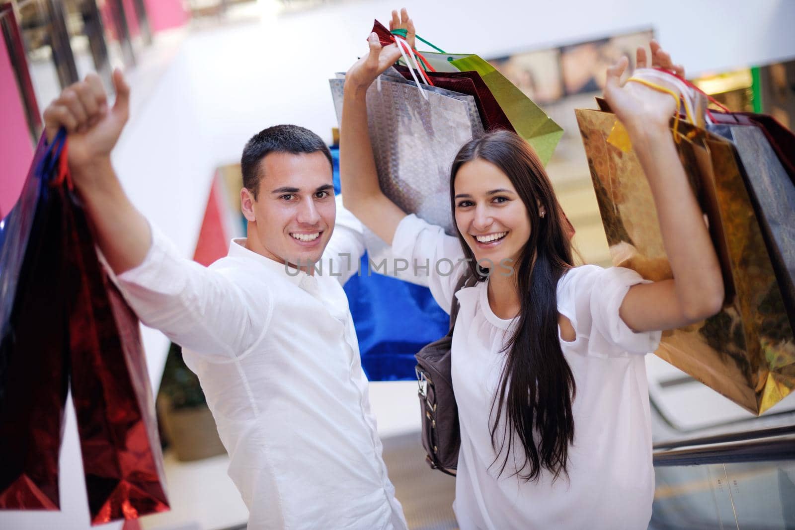 happy young couple with bags in shopping centre mall