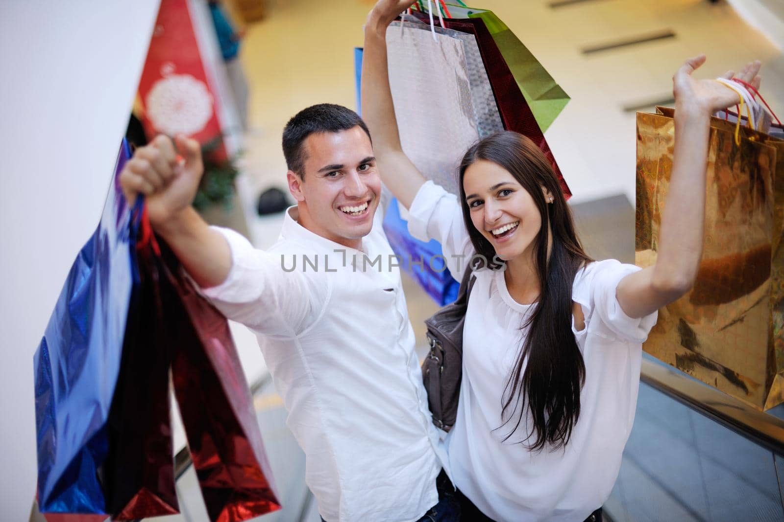 happy young couple with bags in shopping centre mall