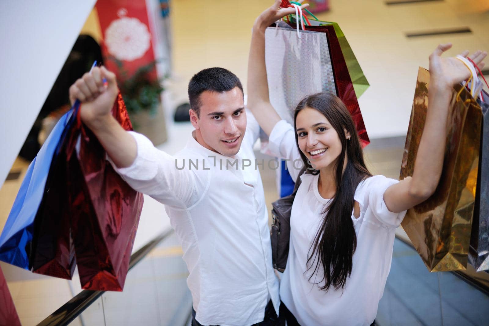 happy young couple with bags in shopping centre mall