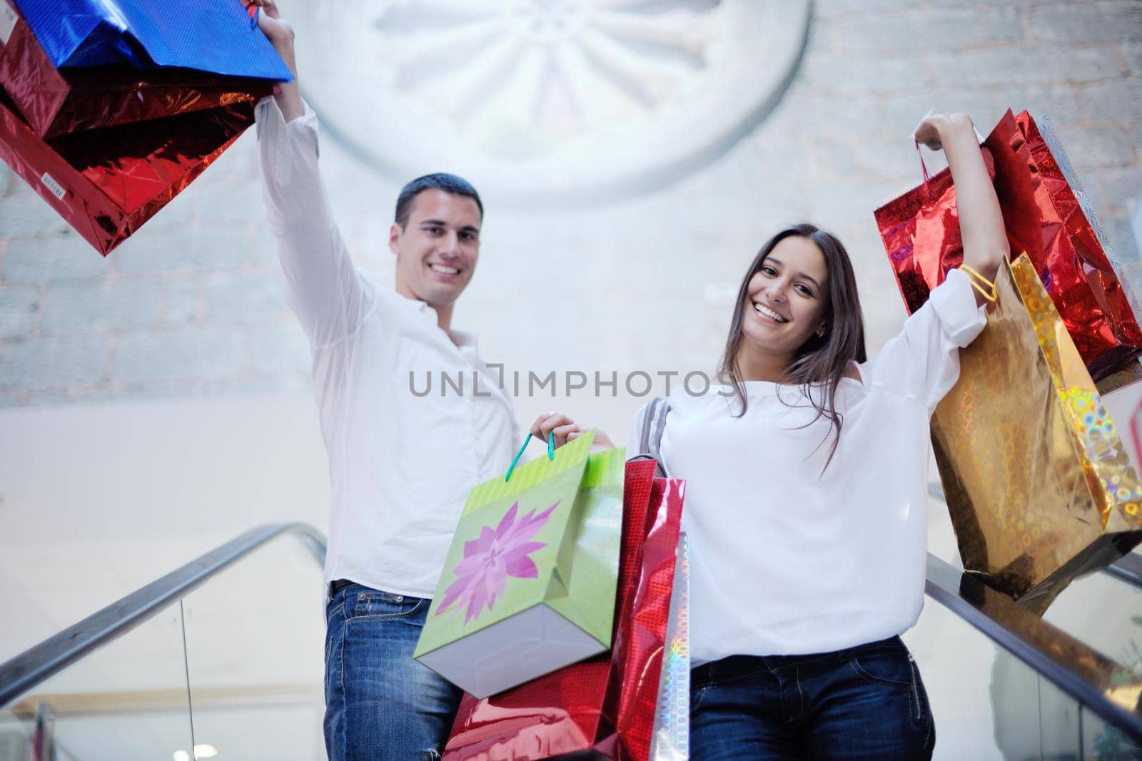 happy young couple with bags in shopping centre mall