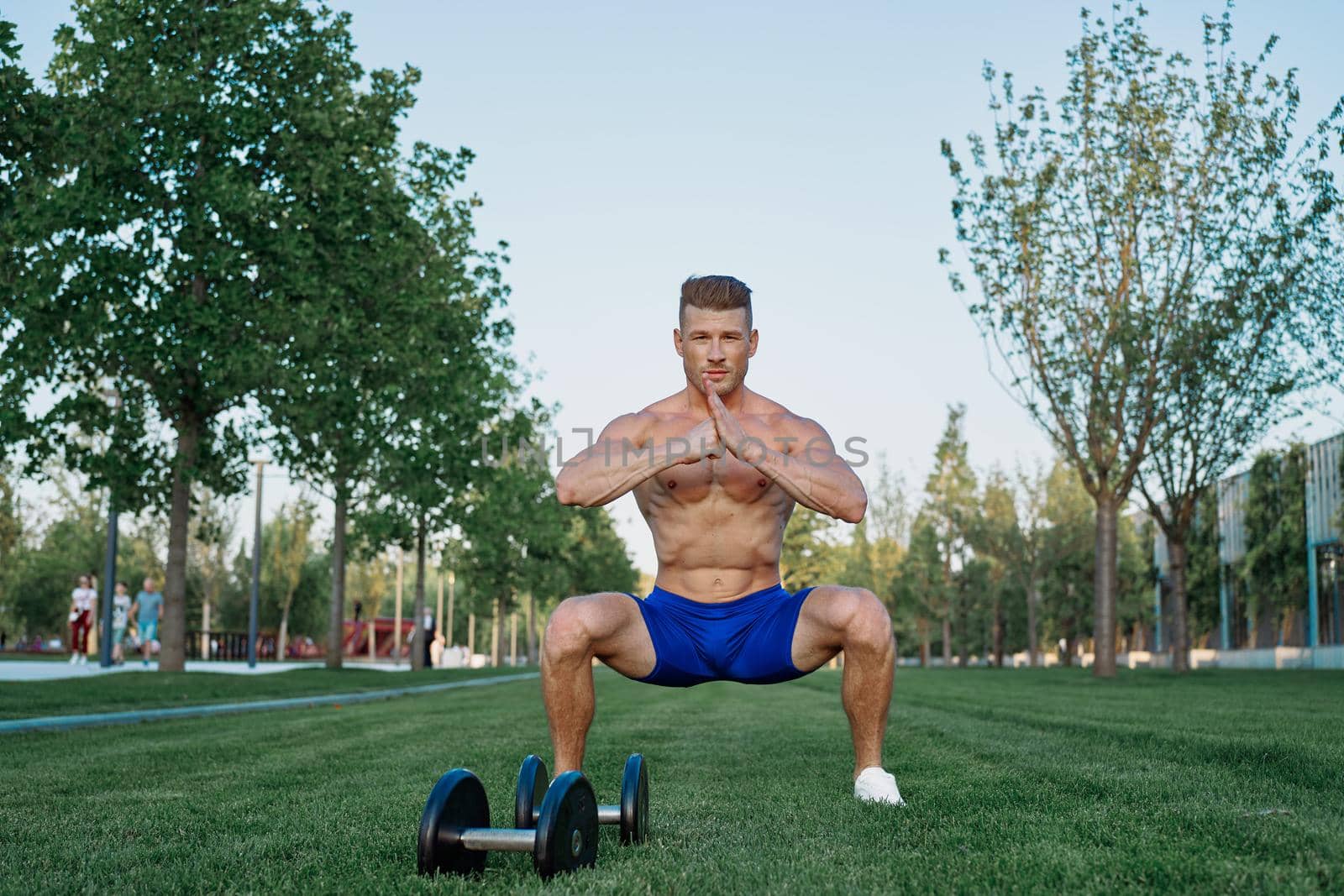 Muscled man in the park training with dumbbells by Vichizh