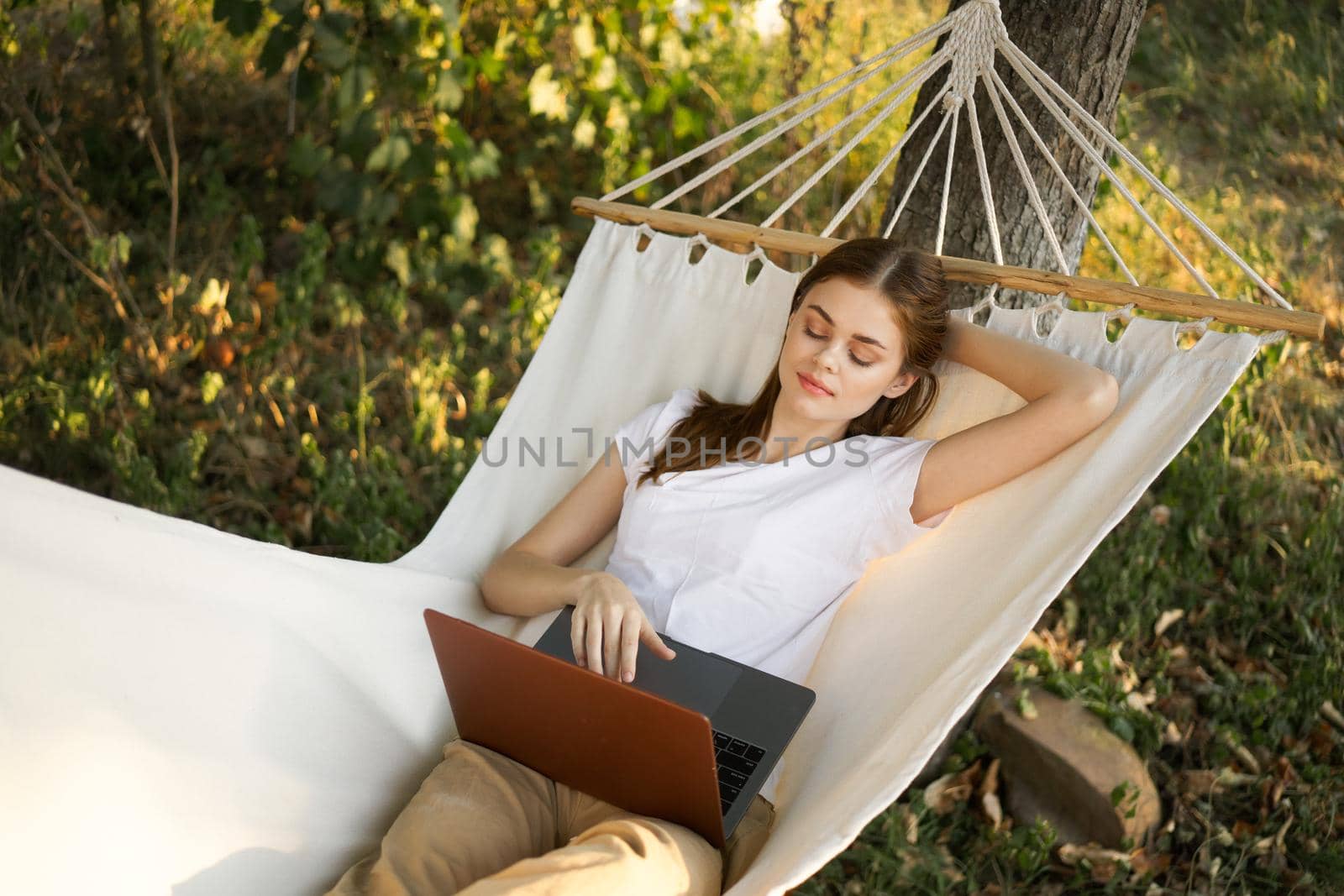 woman lies on a hammock with laptop travel vacation internet by Vichizh