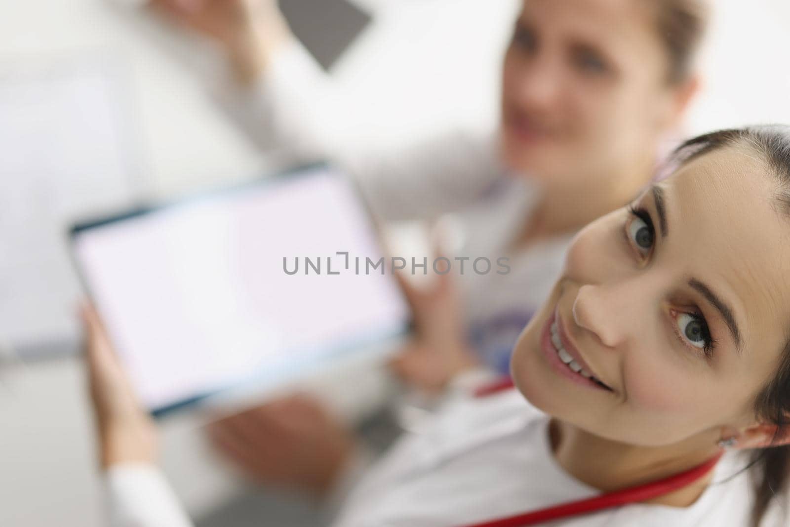 Top view of women working in hospital spend pause with tablet device. Smiling nurse hold gadget with white screen. Pause from work, pastime, clinic concept