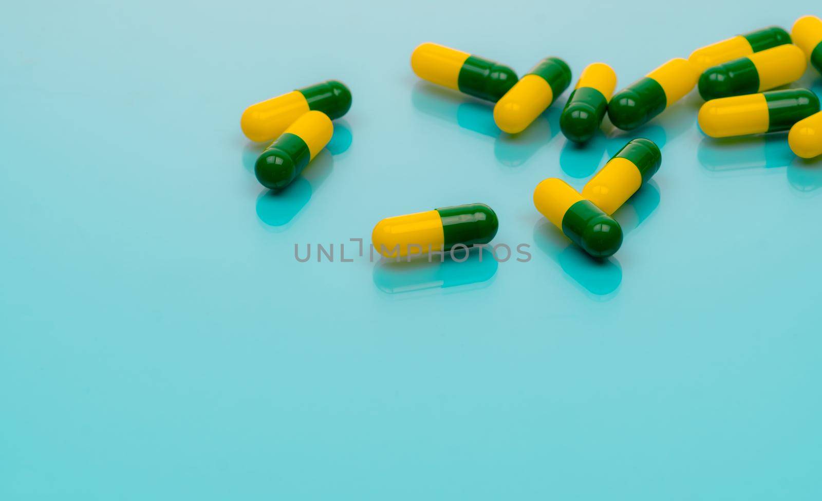 Tramadol pills. Green-yellow capsule pills on blue background. Tramadol is a strong painkiller medicine used to treat moderate to severe pain. Background for tramadol misuse topics. Opioids drug. by Fahroni