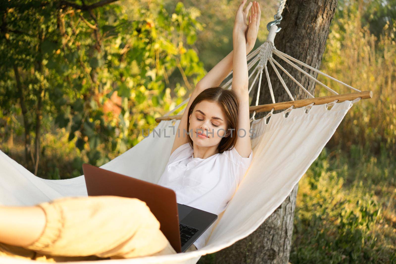 women outdoors lies in a hammock with a laptop freelance internet. High quality photo