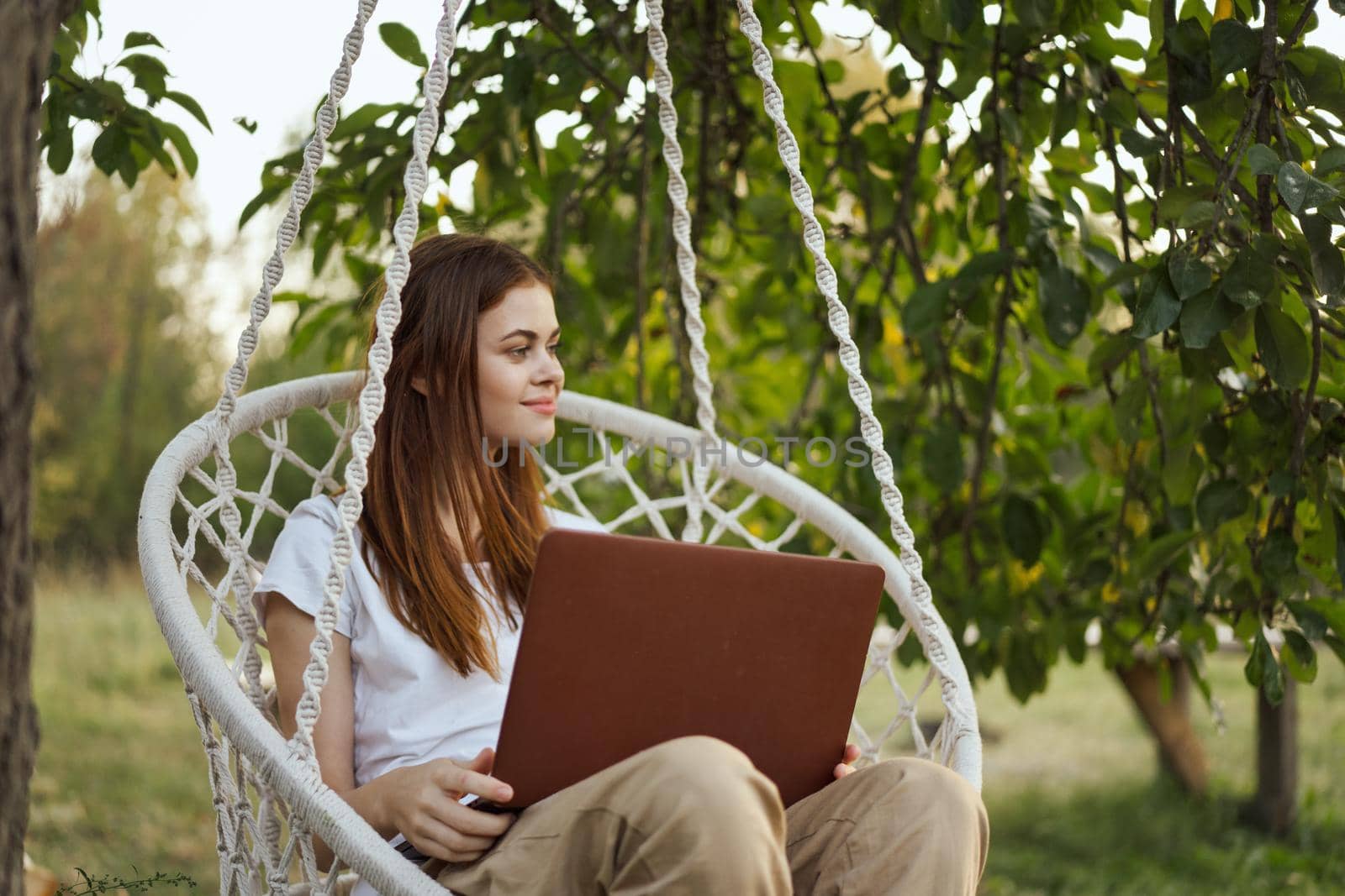 woman with laptop outdoors resting in hammock internet. High quality photo