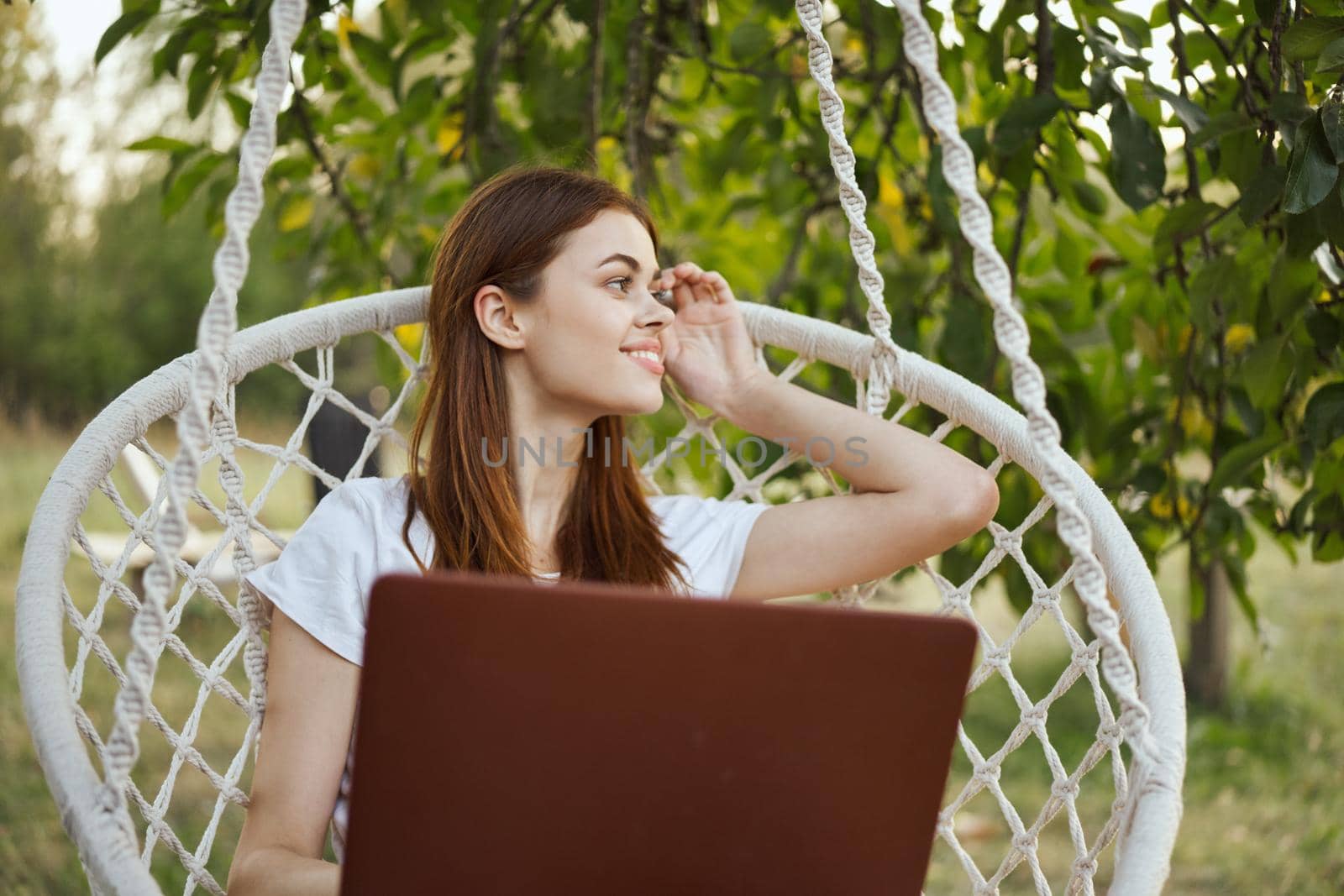 smiling woman outdoors in hammock with laptop technology. High quality photo