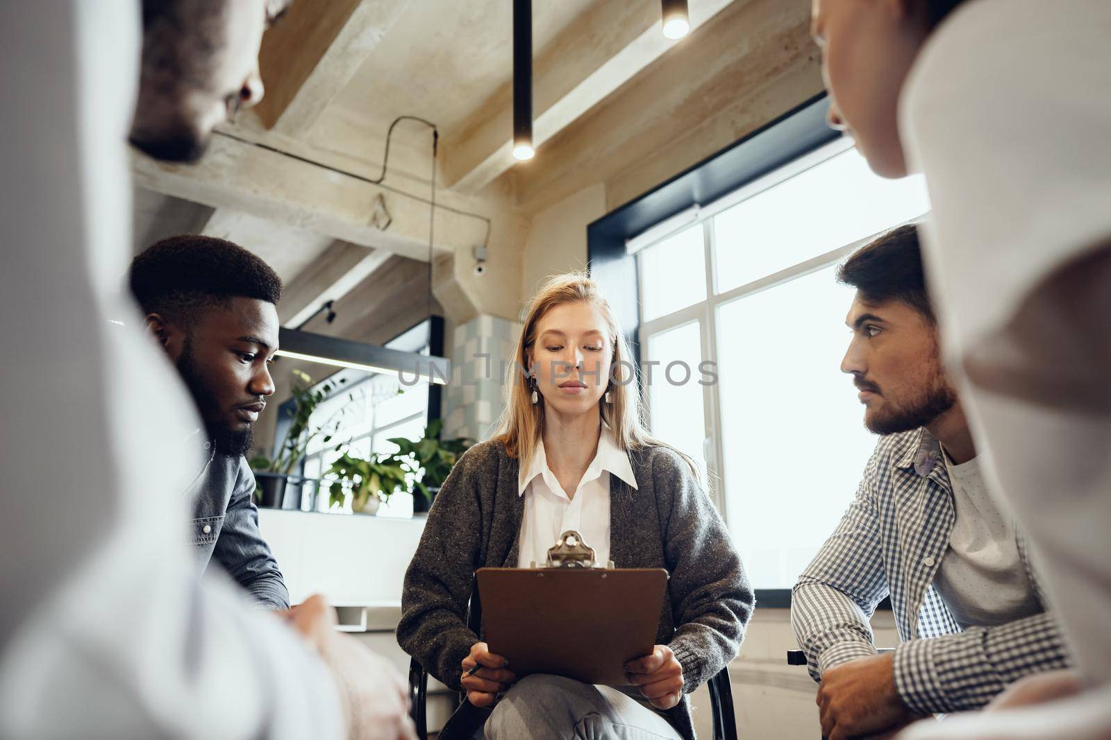 Young people sitting in a circle and having a discussion by Fabrikasimf