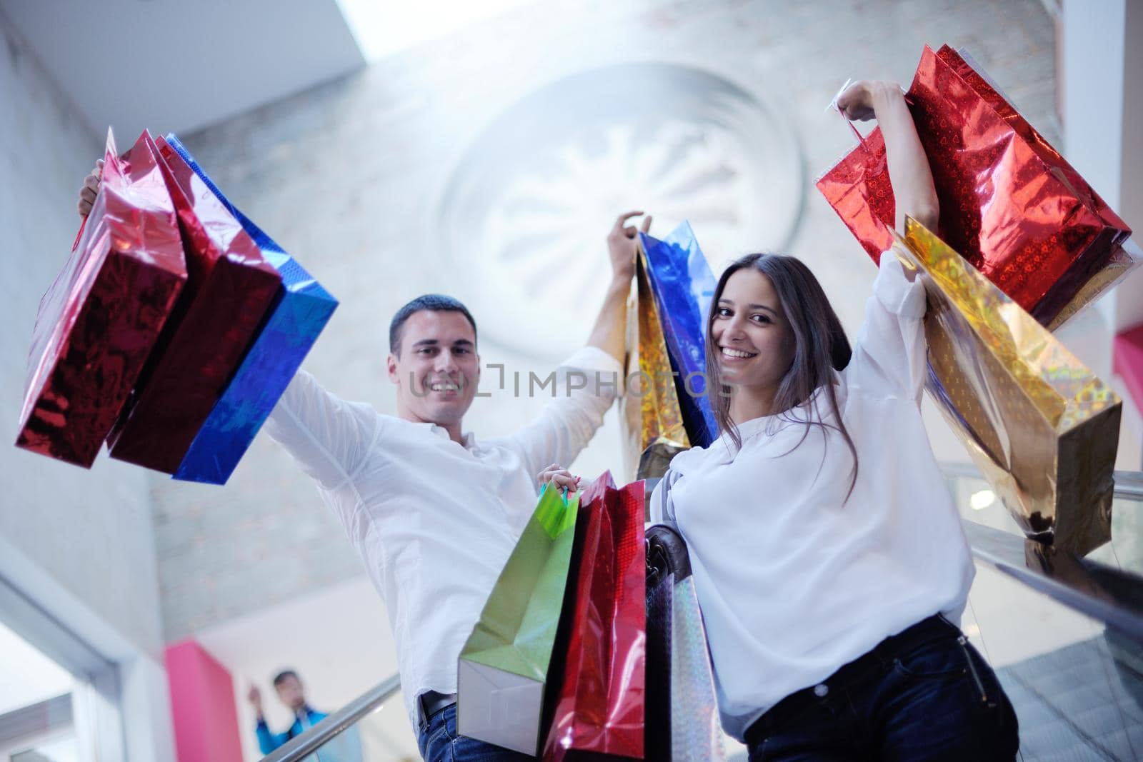 happy young couple with bags in shopping centre mall