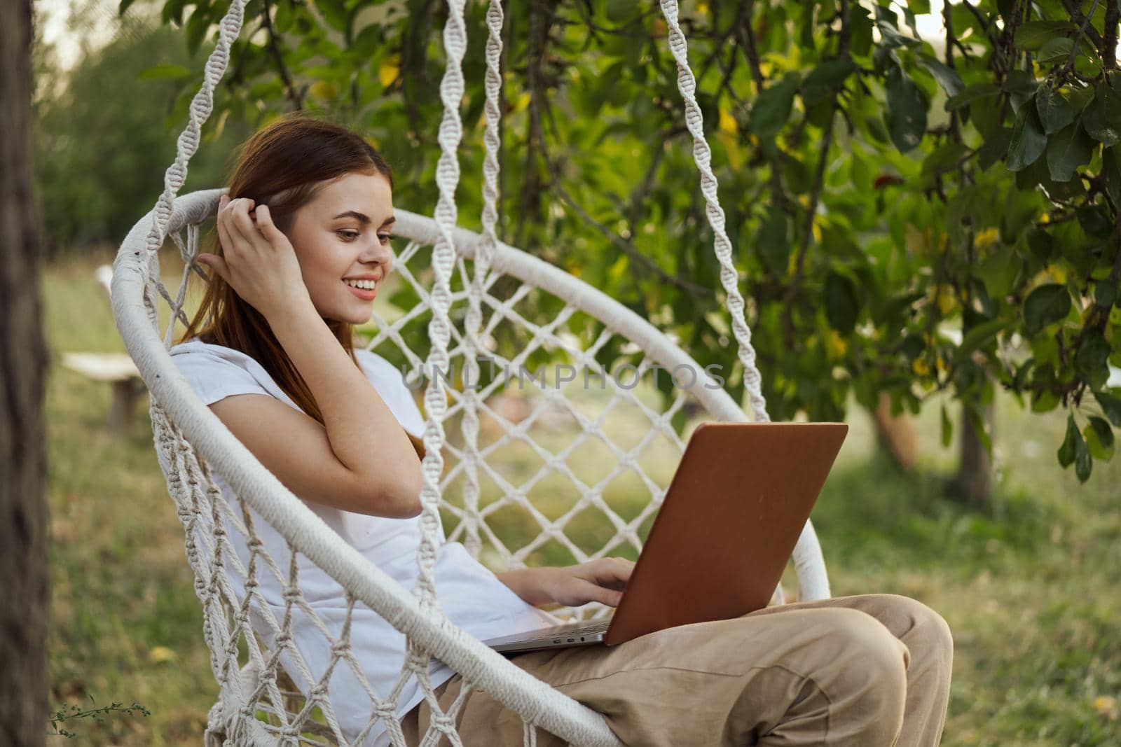 woman with laptop outdoors resting in hammock internet. High quality photo