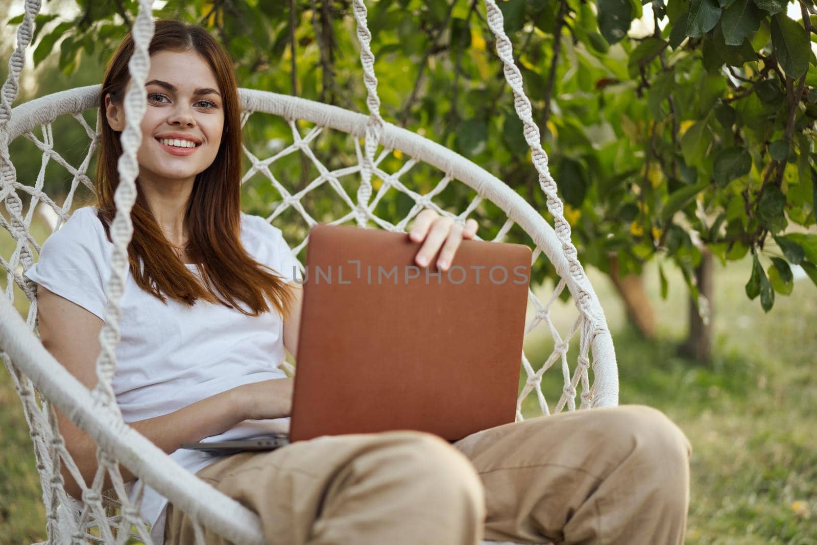 smiling woman outdoors in hammock with laptop technology by Vichizh