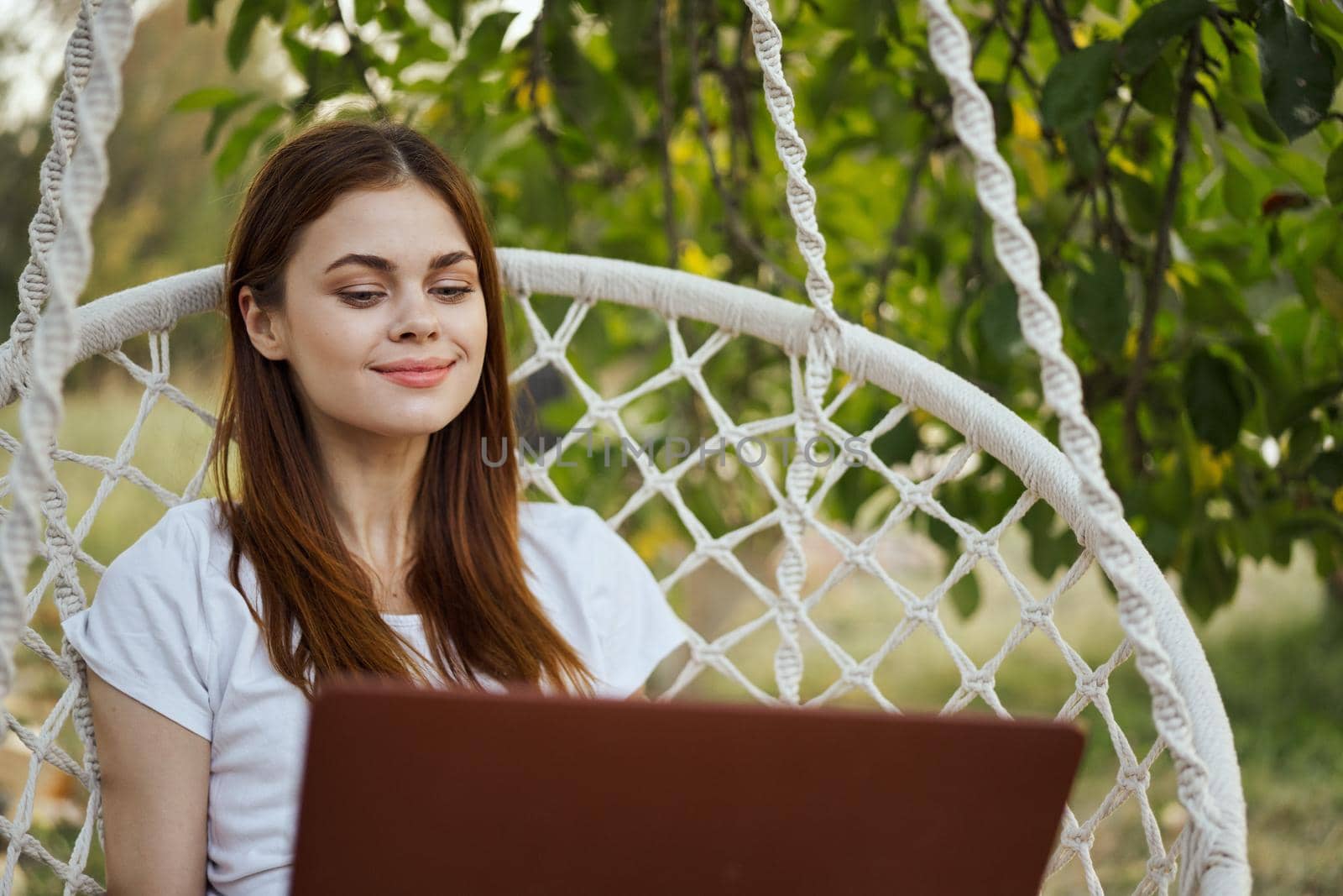 smiling woman outdoors in hammock with laptop technology. High quality photo