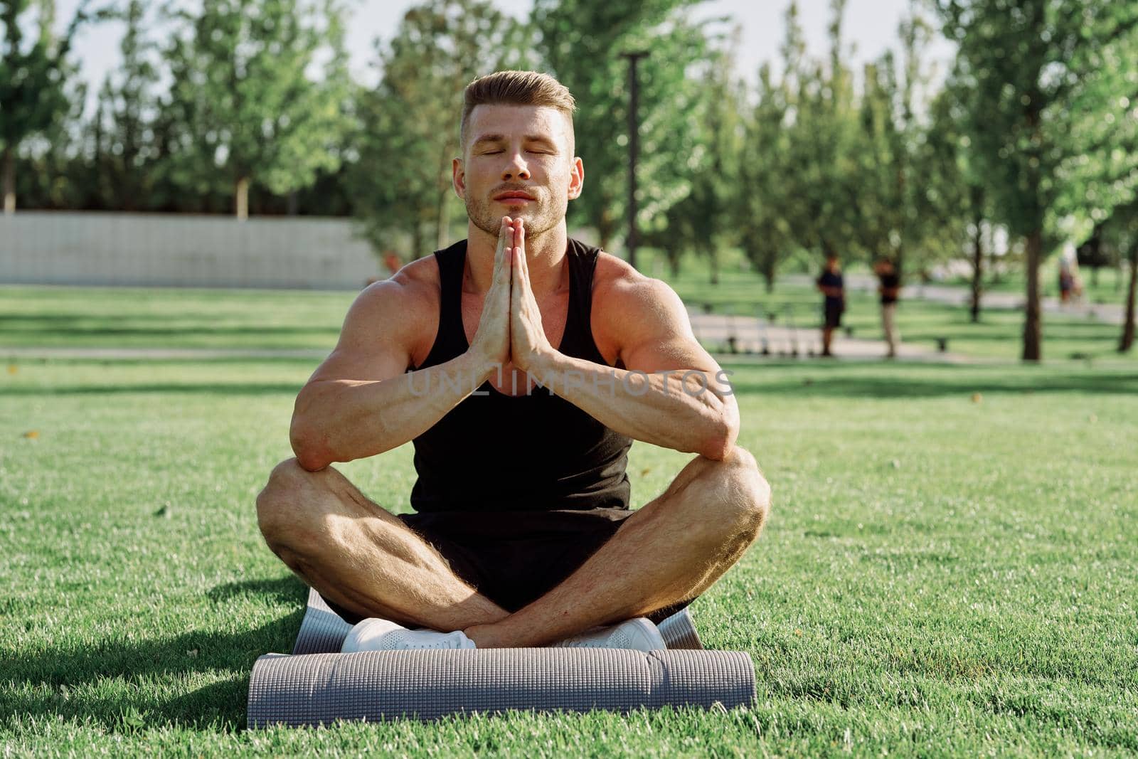 sporty man sitting on the lawn in the park training. High quality photo