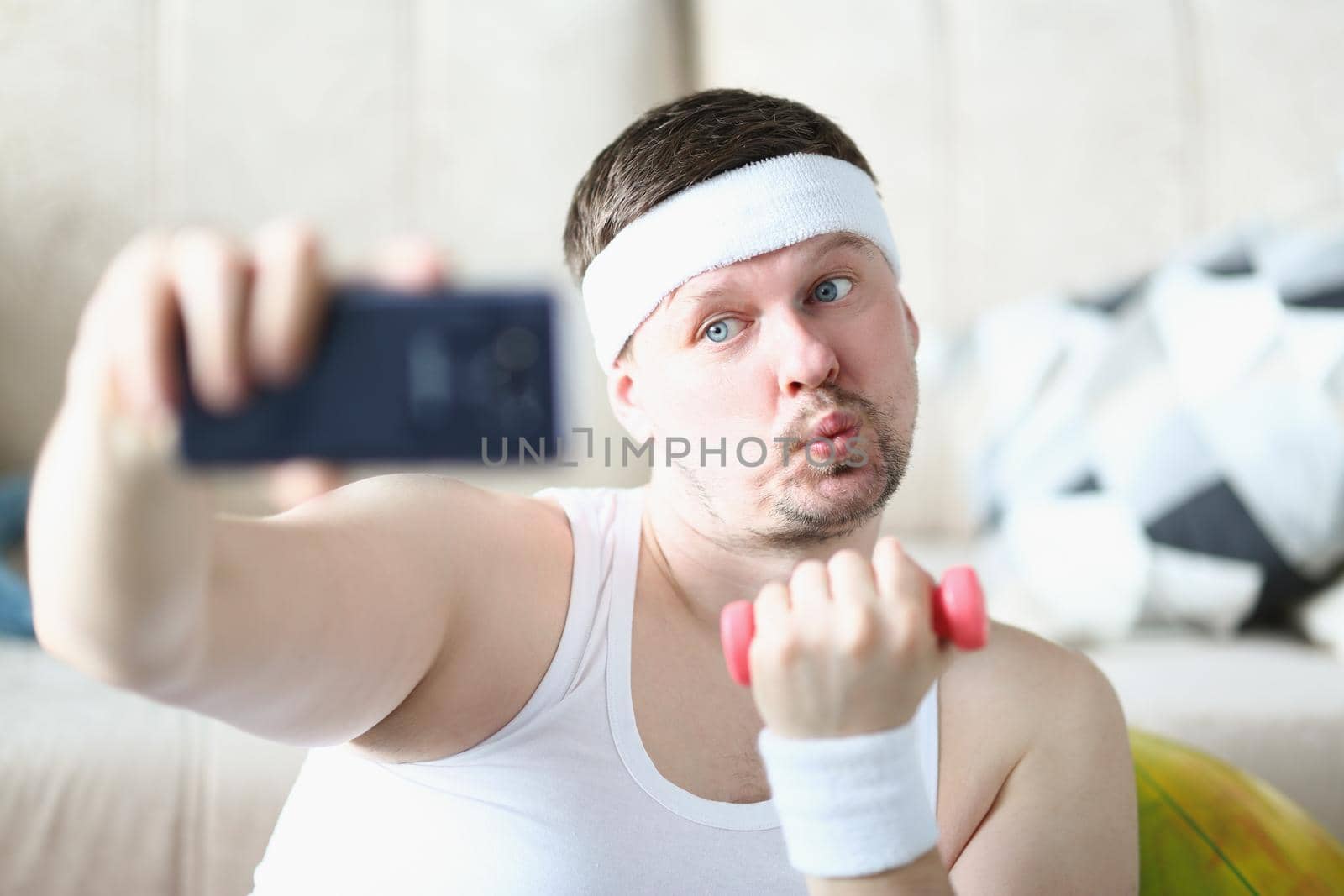 Portrait of sportsman training at home lifting dumbbell and take selfie for social media channel. Middle aged blogger create sport content. Hobby concept