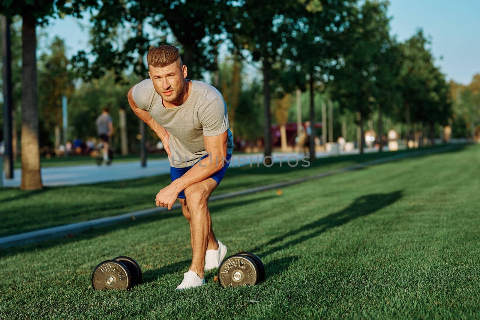 male athlete park with dumbbells doing CrossFit exercise by Vichizh