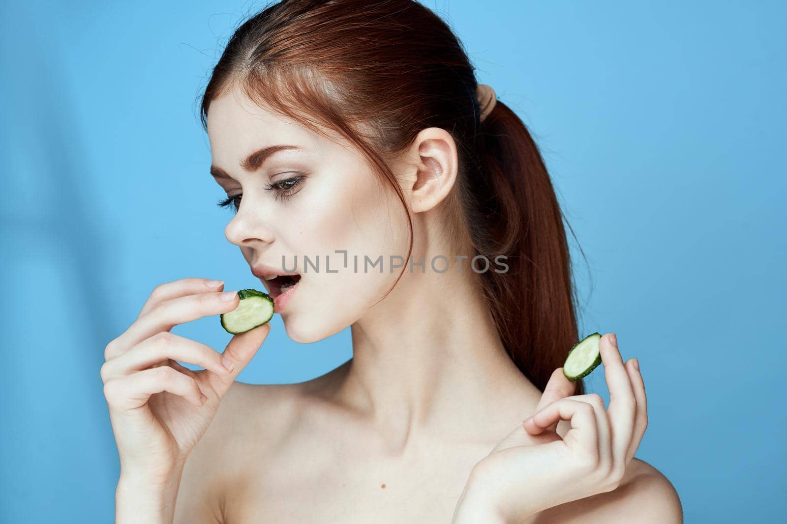 woman with bare shoulders cucumber vitamins health blue background by Vichizh