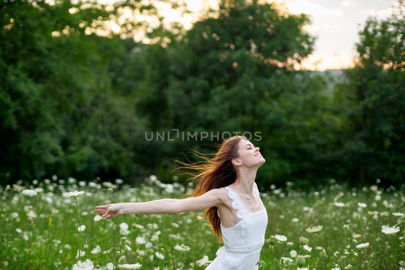 cheerful woman in a field with flowers in a white dress in nature by Vichizh