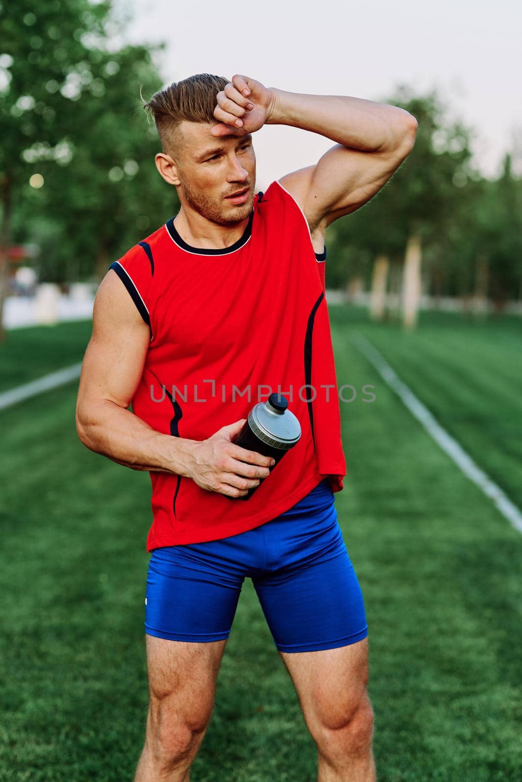 Cheerful sporty man in the park on green grass doing exercises by Vichizh