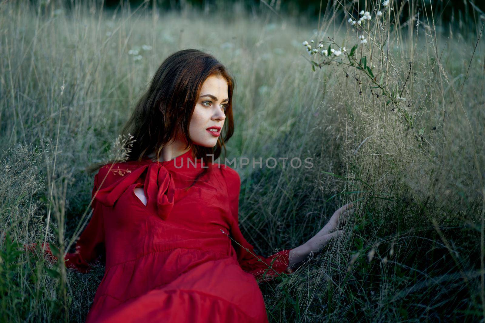 woman in red dress lies on the grass nature freedom rest. High quality photo