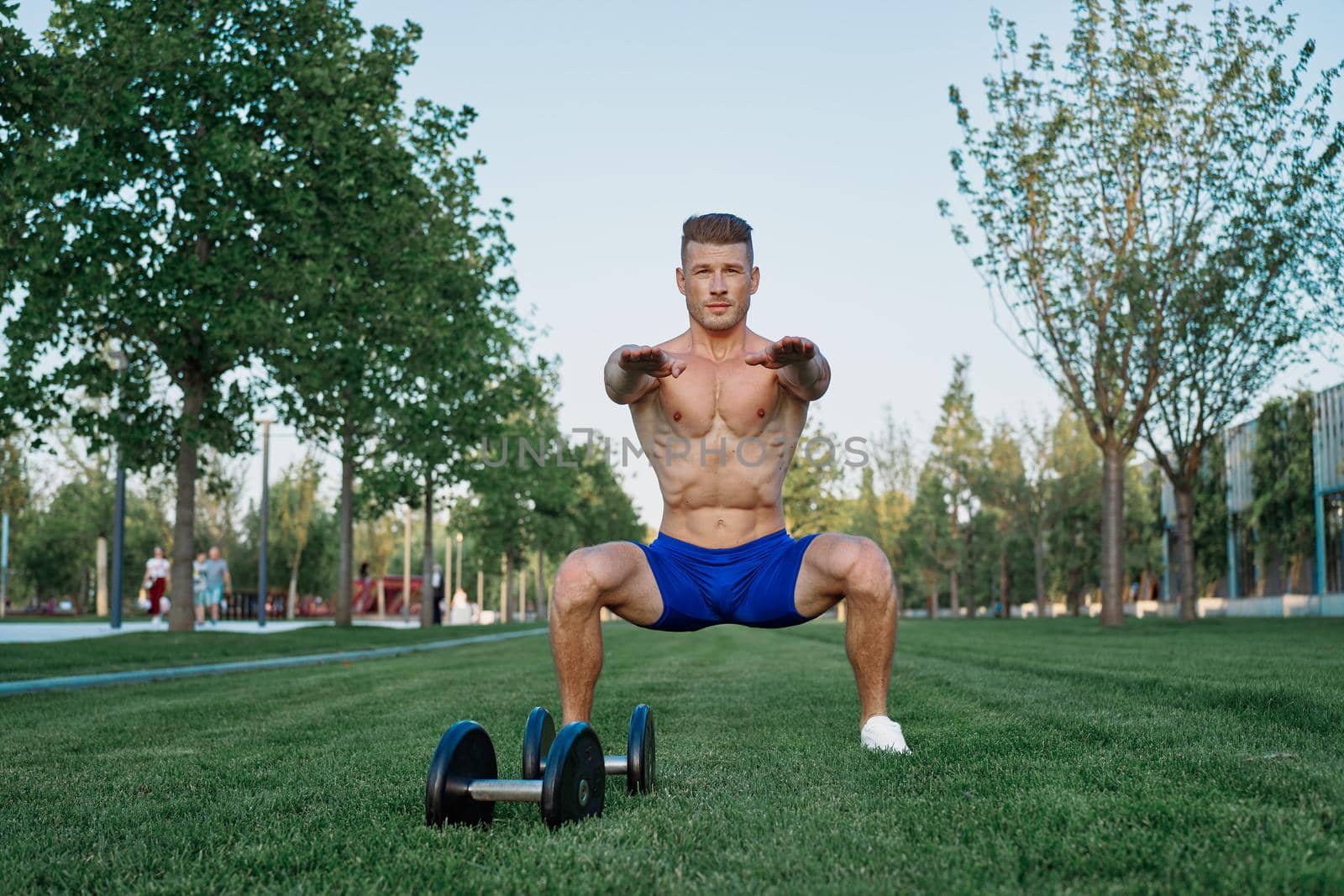 Muscled man in the park training with dumbbells. High quality photo