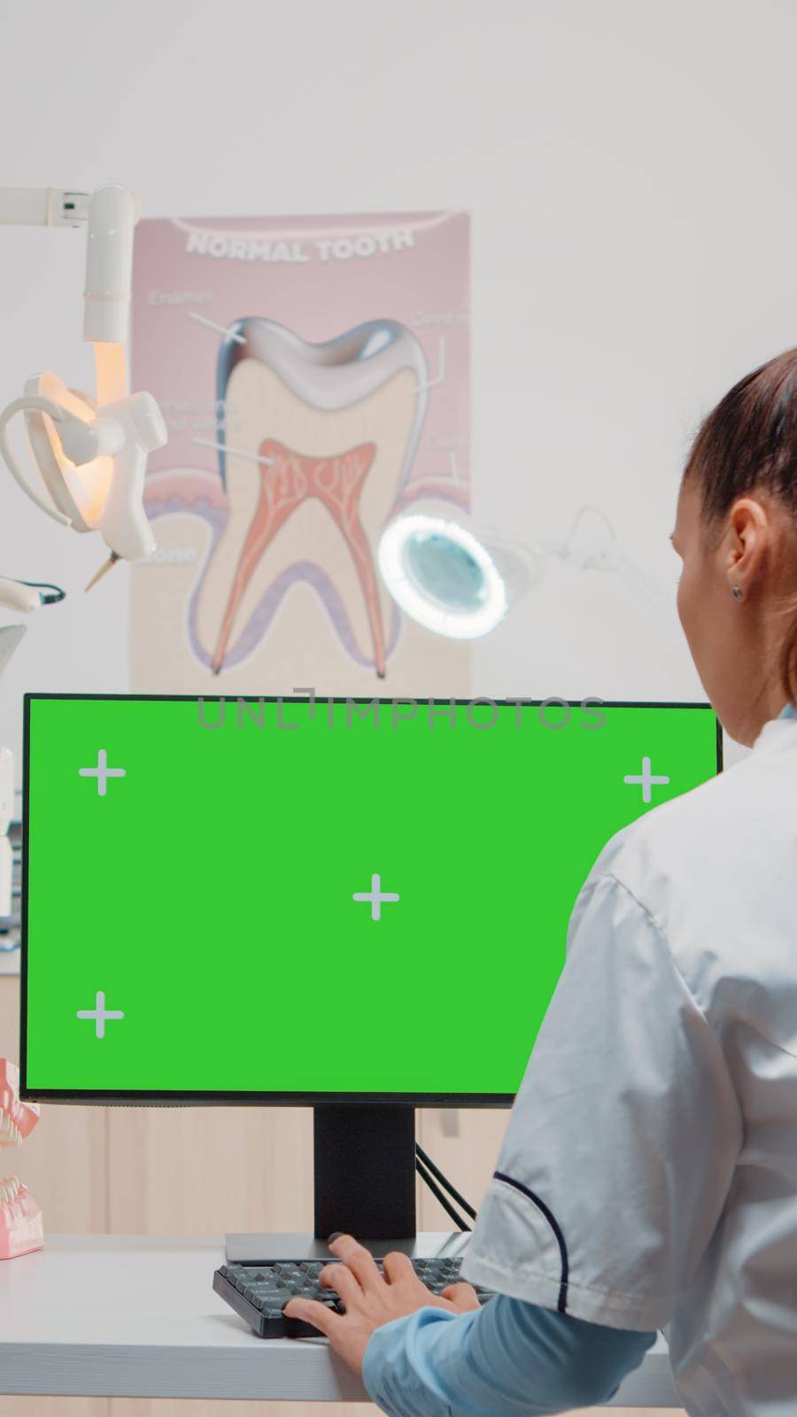 Dentist using computer with horizontal green screen on display by DCStudio