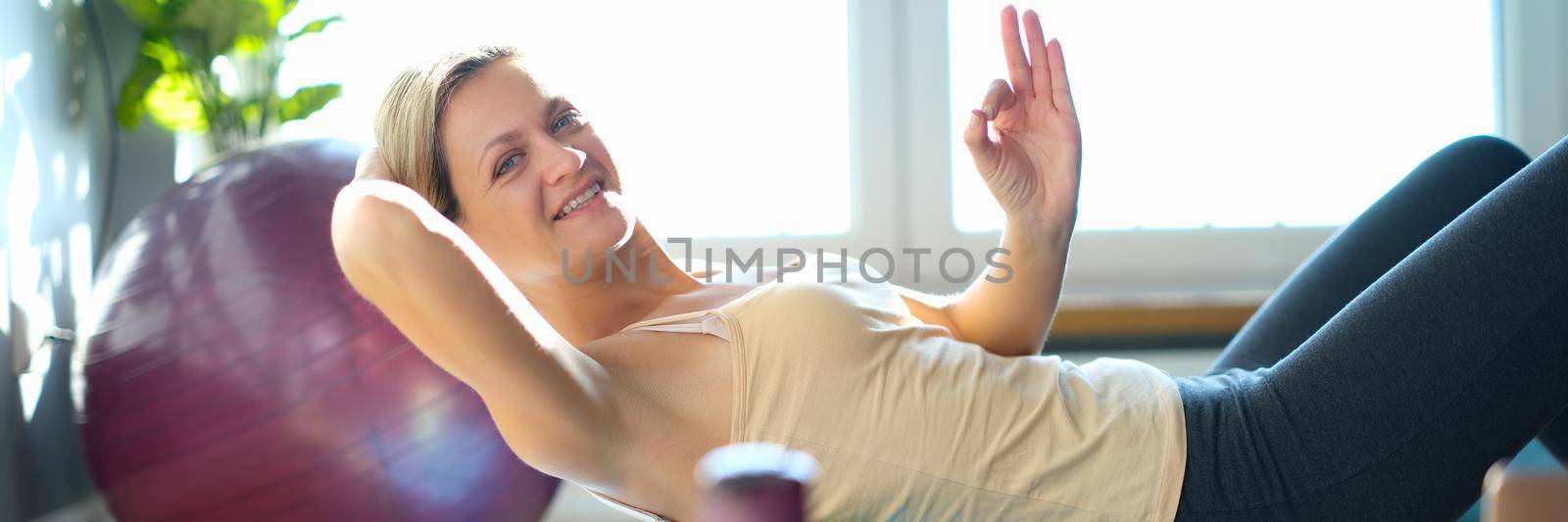 Smiling woman doing exercises on back roller by kuprevich