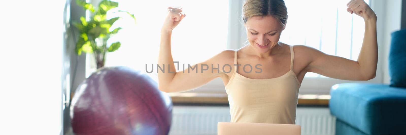 Young happy woman repeats physical exercises look at laptop. Remote self-practice sports concept