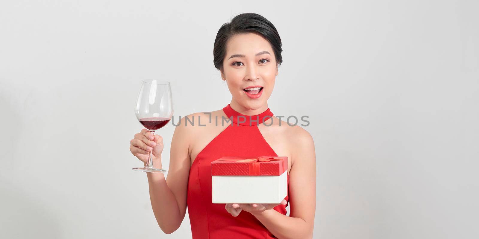 Young attractive woman in evening dress holding gifts red boxes on white background. New Year/Birthday/Anniversary celebration, holiday concept, excitement and admiration by makidotvn