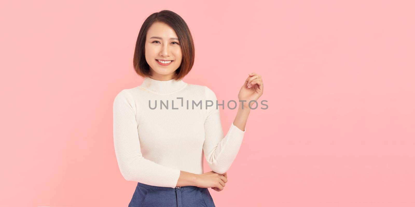 woman looking at camera and smiling while standing against pink background. by makidotvn