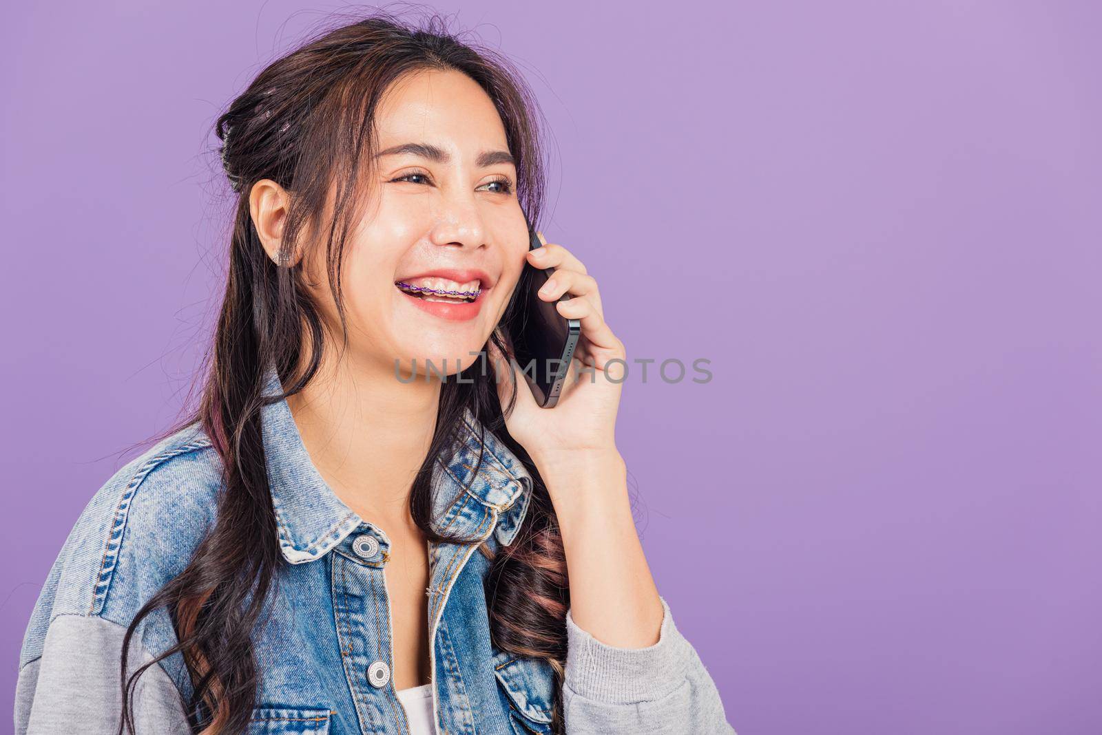 
Portrait of Asian beautiful young woman confident smiling on phone call with smartphone, Happy lifestyle female teen calling and talking to her friends, studio shot isolated on purple background