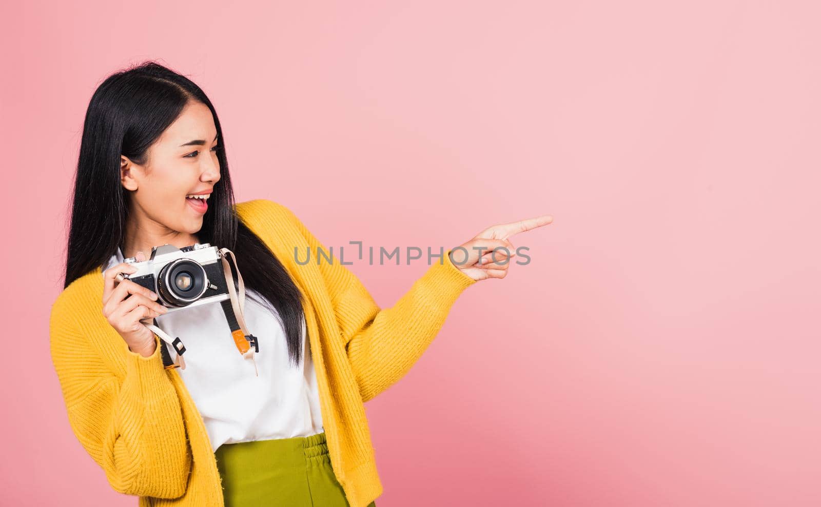 woman teen excited smiling holding vintage photo camera and pointing finger by Sorapop