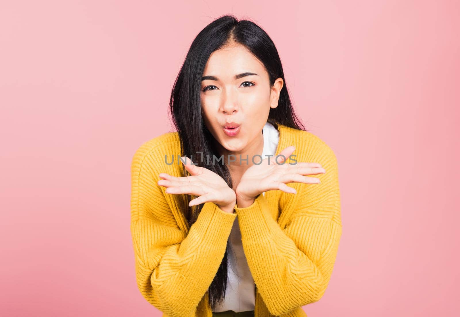 Asian happy portrait beautiful cute young woman teen standing blowing kiss air something on palm hands expresses her love looking to camera studio shot isolated on pink background with copy space