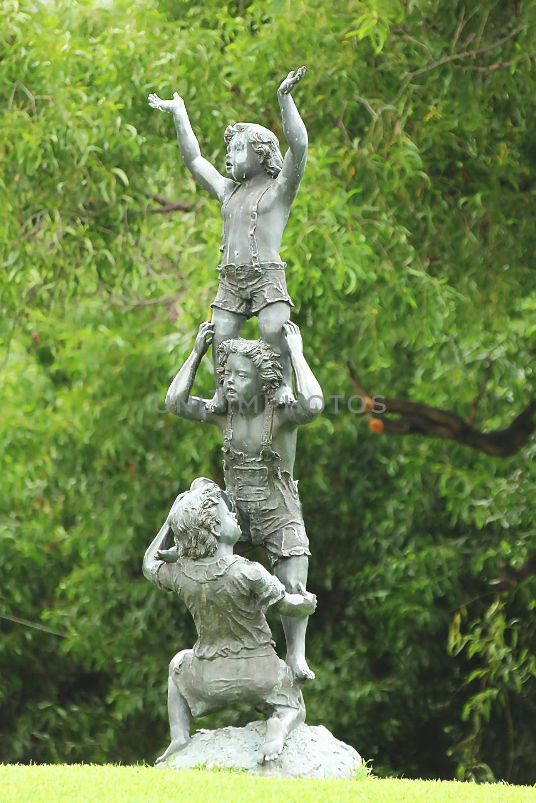 A statue of a child doing acrobatics is located in the park.