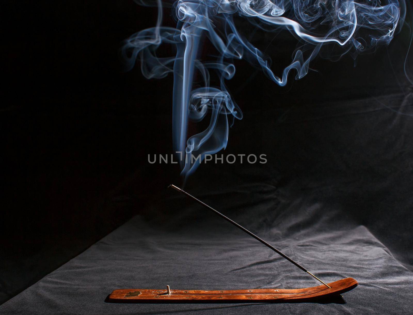 indian incense stick with smoke on black background indoor closeup