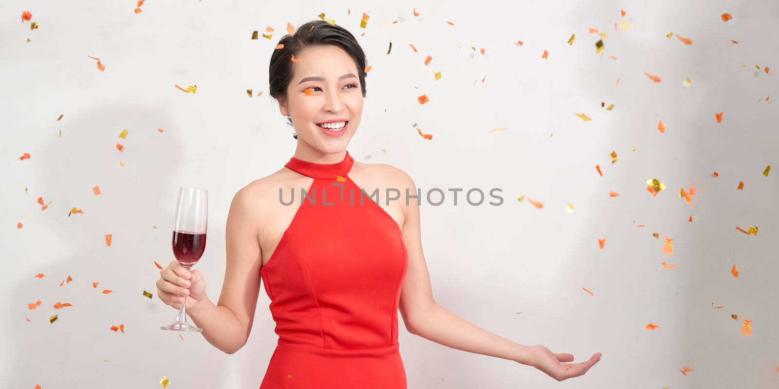 Attractive girl in stylish party attire raising wineglass during event.  by makidotvn