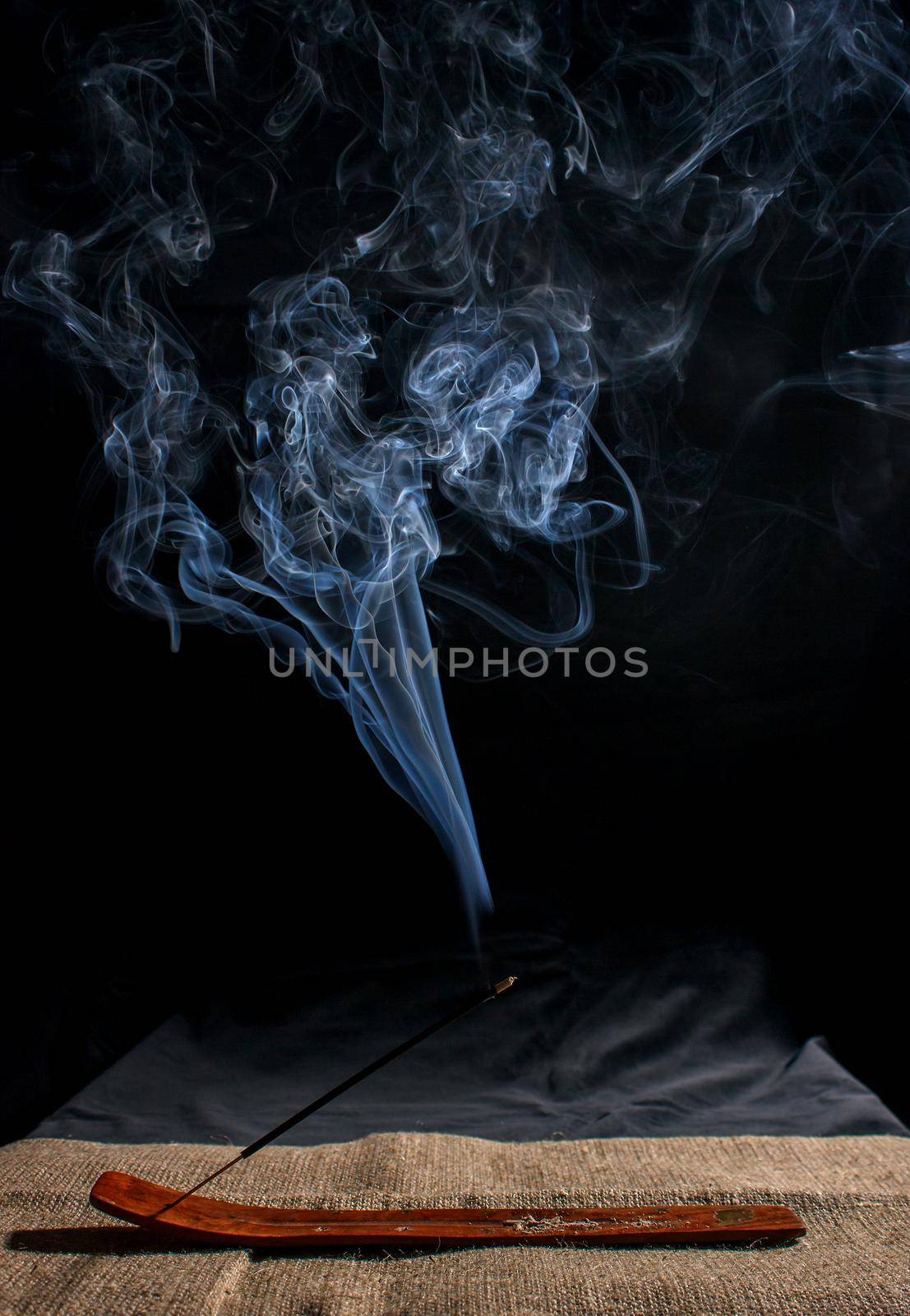 indian incense stick with smoke on black background indoor closeup