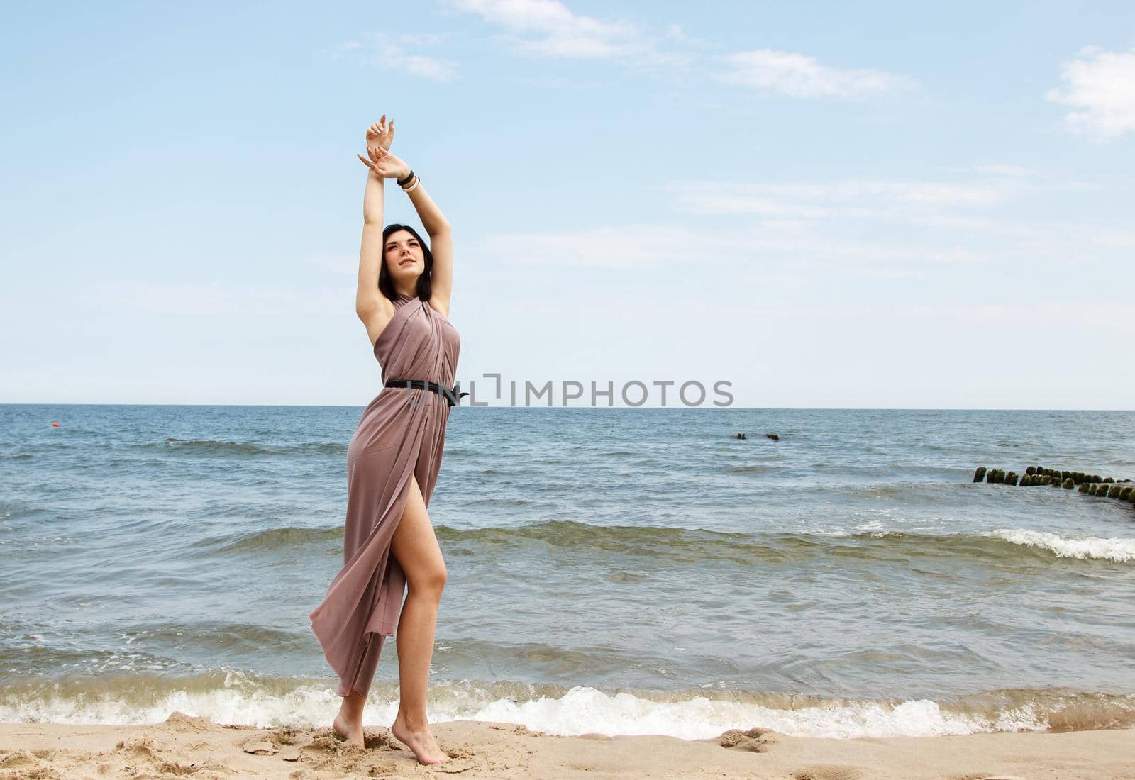 young brunette woman stands on the sand by the sea by raddnatt