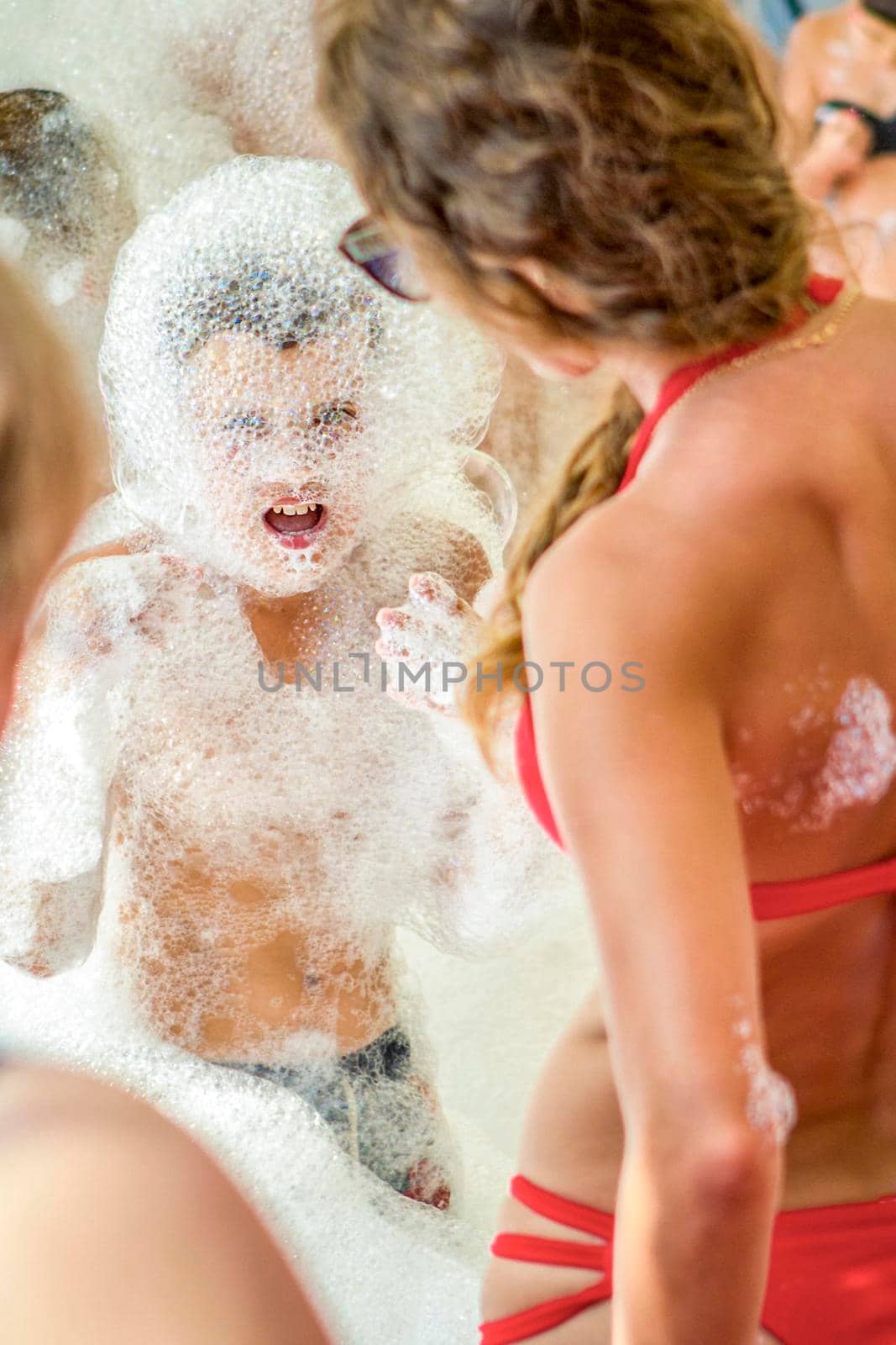 Young boy at the foam party. The face and body are covered with foam. Holiday concept.