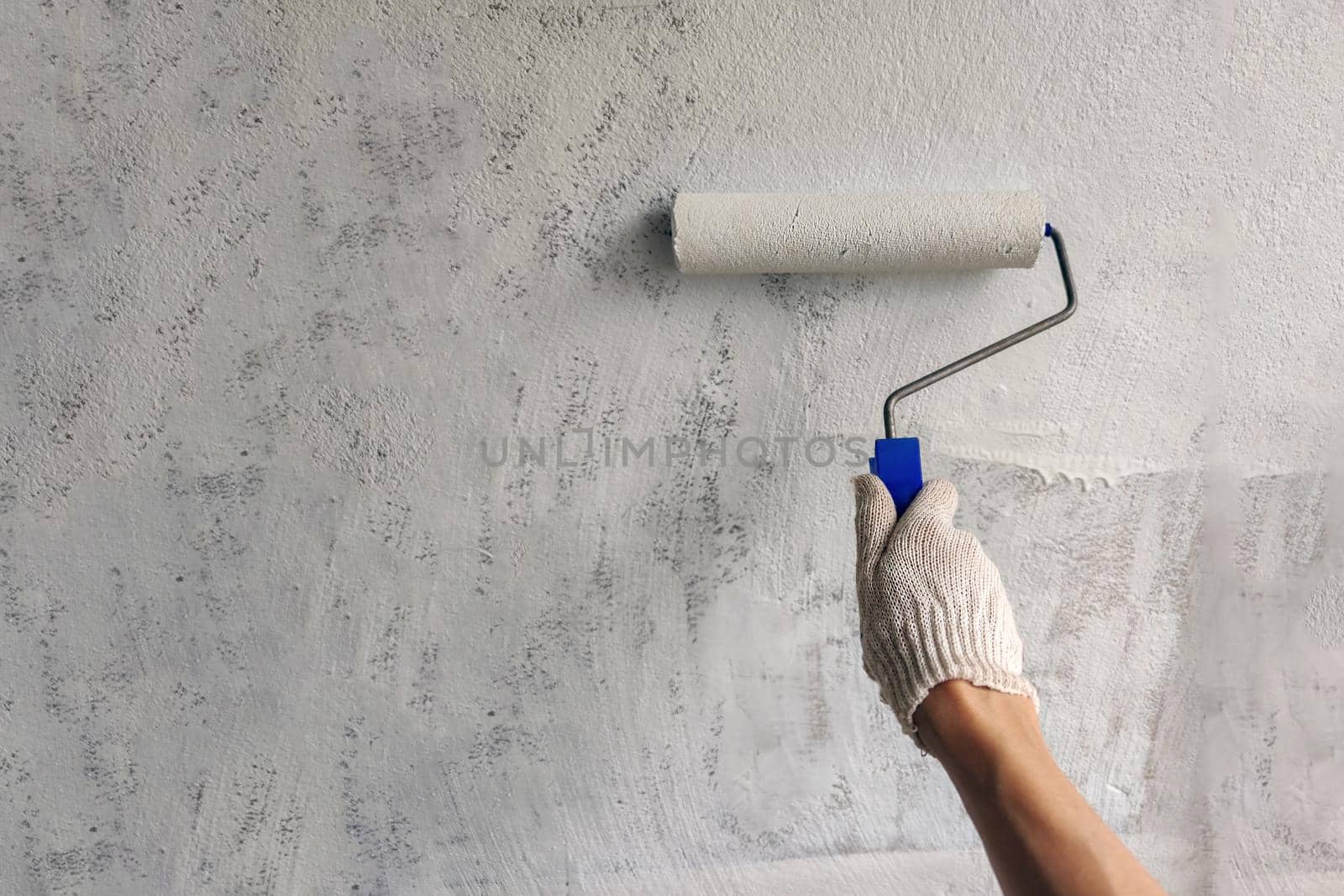 A girl paints wall with white paint. Hand with roller. by Laguna781