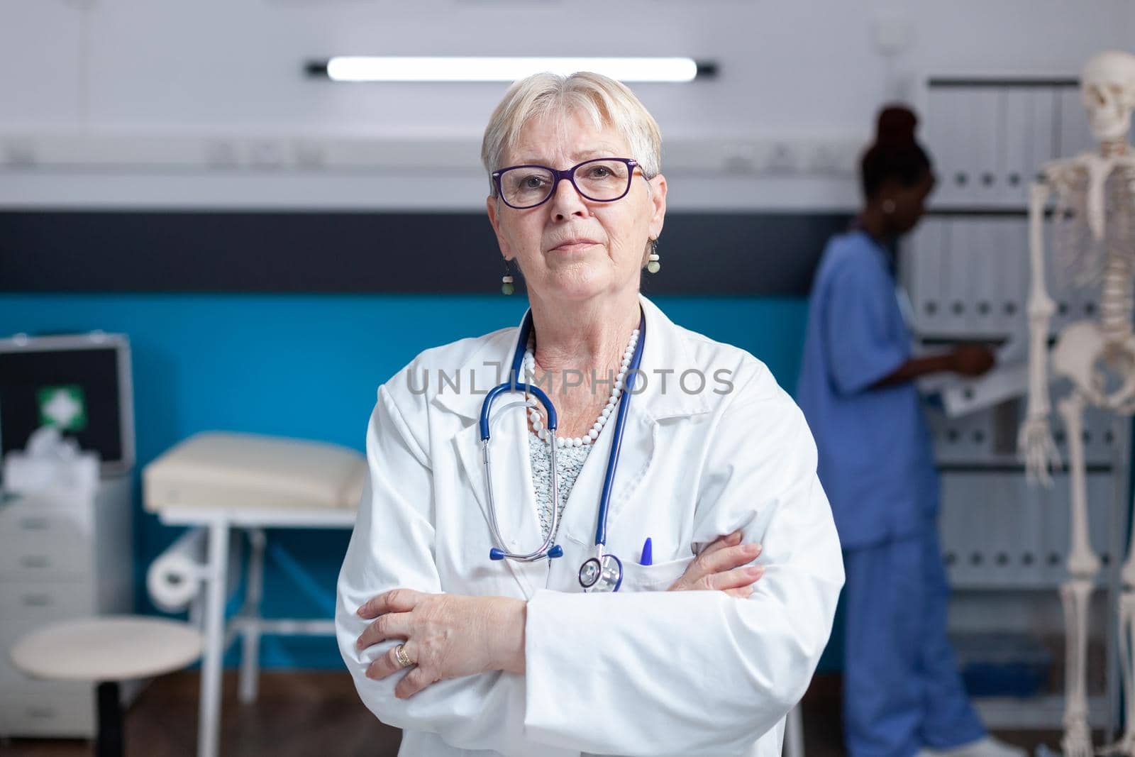 Portrait of senior medic standing with arms crossed in healthcare cabinet, having stethoscope. Close up of specialist ready to practice medicine and medical expertise. Confident woman doctor