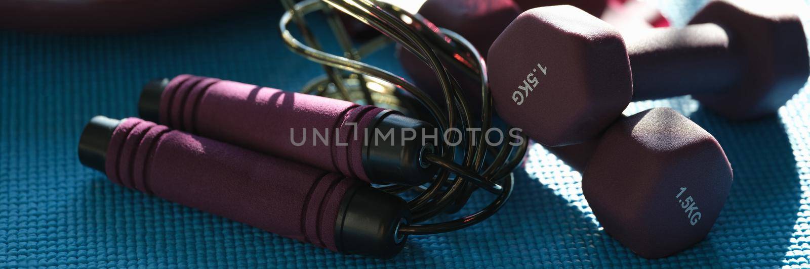Sports accessories dumbbell skipping rope lie on mat. Daily sports concept