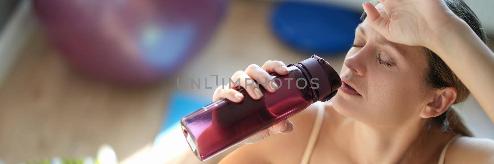 Tired young woman drinks water after training closeup by kuprevich