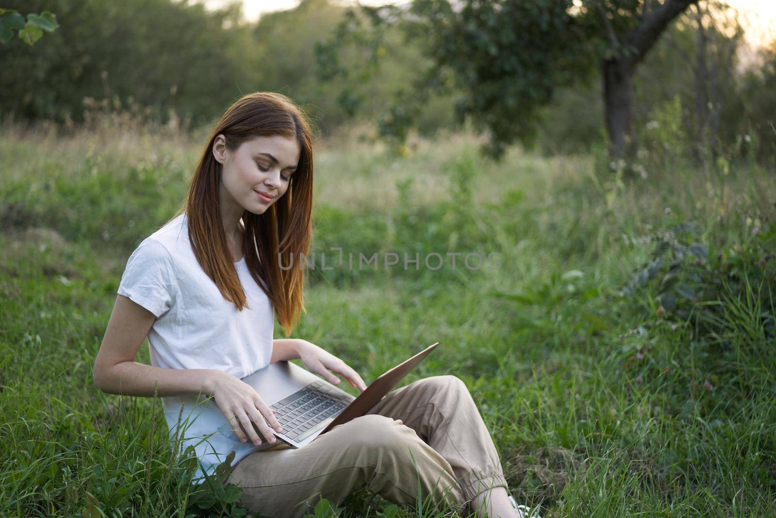 women outdoors in field with laptop leisure technology freedom. High quality photo