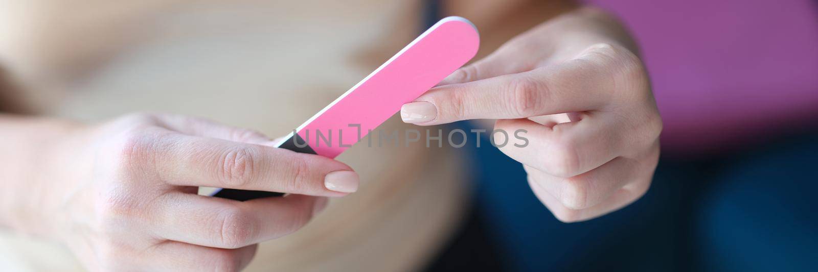 Woman files fingernails with pink nail file. Choosing reliable quality nail file concept