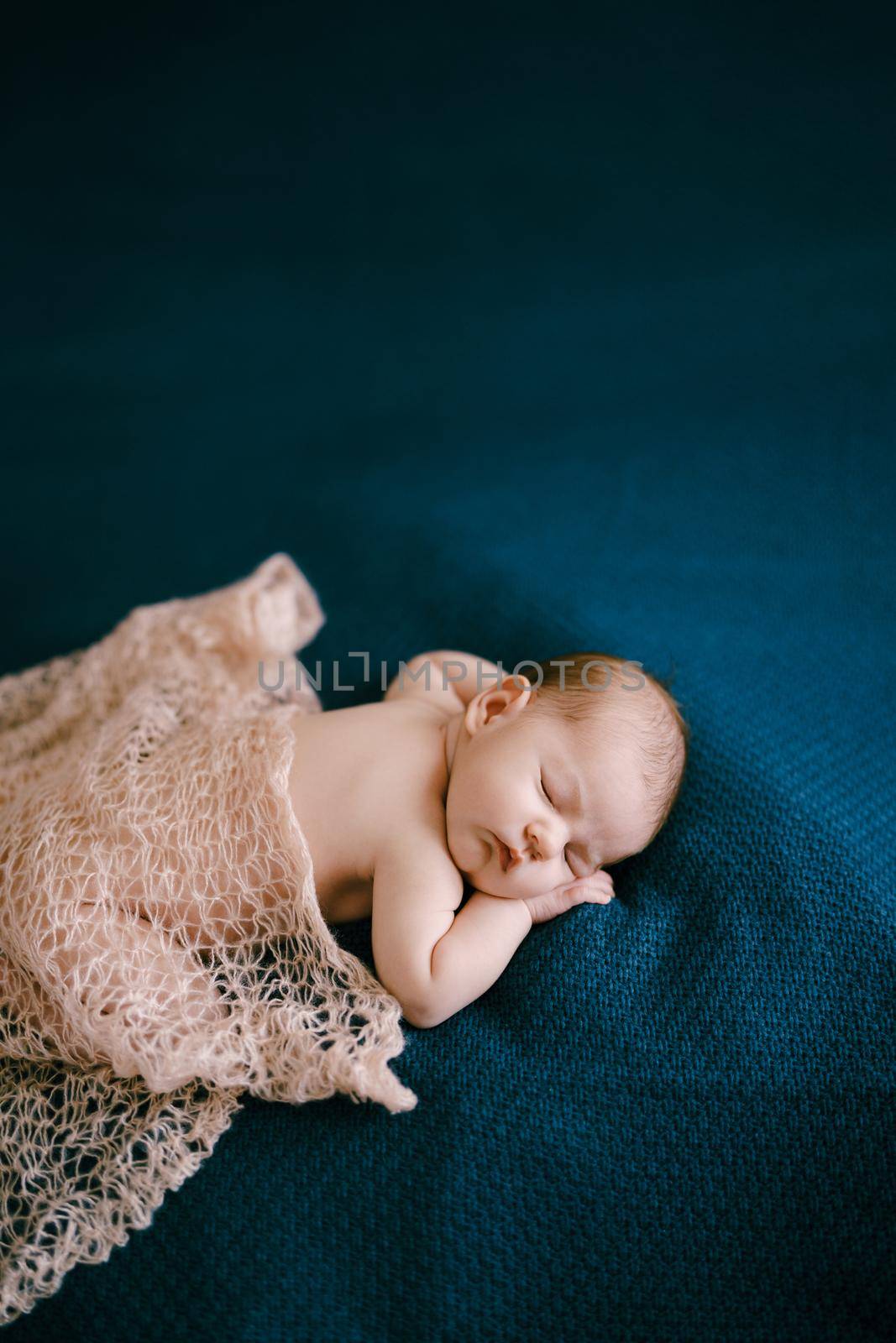 Naked baby covered with shawl sleeps on blanket. High quality photo
