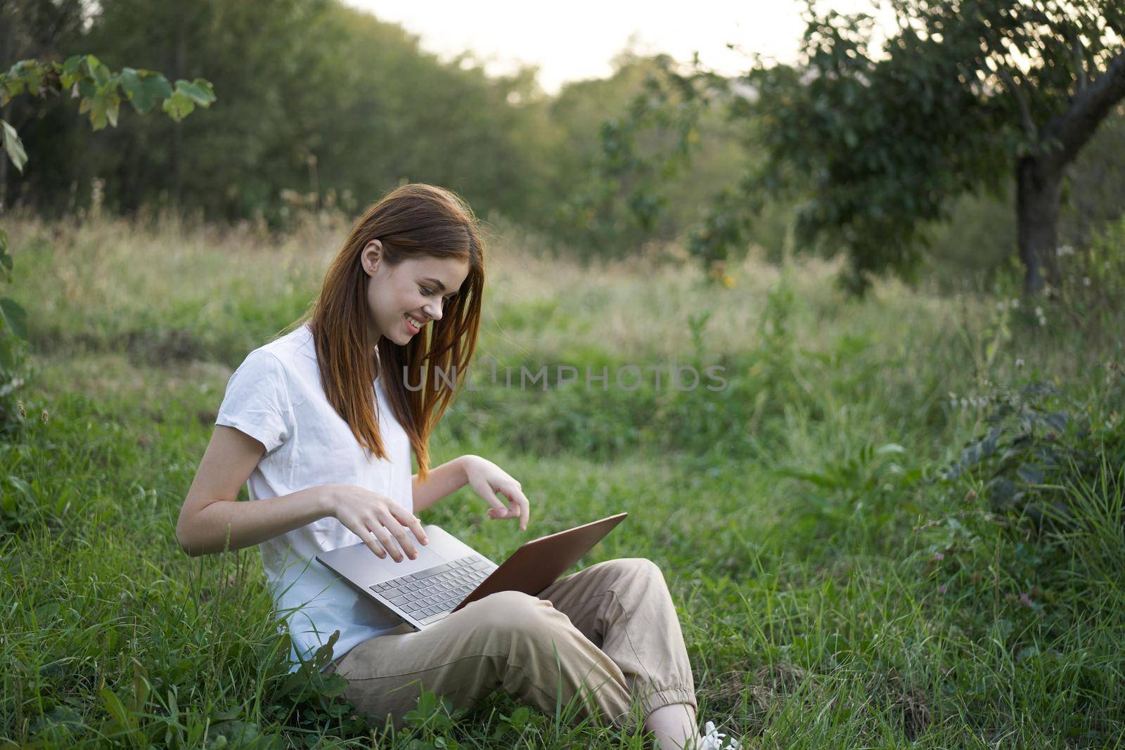 women outdoors in field with laptop leisure technology freedom. High quality photo