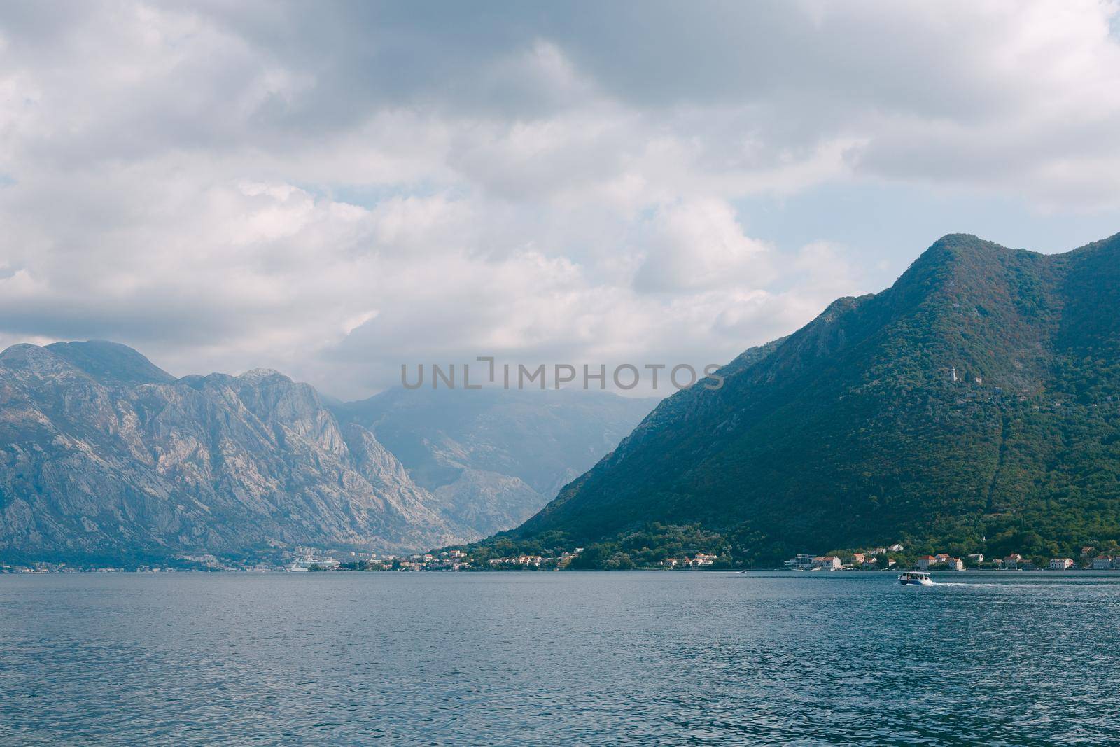 Boat sails along the Bay of Kotor against the backdrop of mountains. View from Perast by Nadtochiy