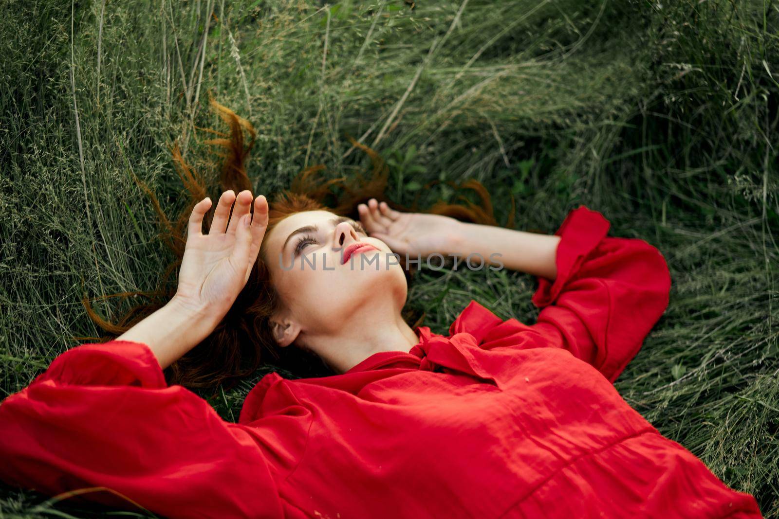 woman in red dress lies on the grass charm freedom. High quality photo