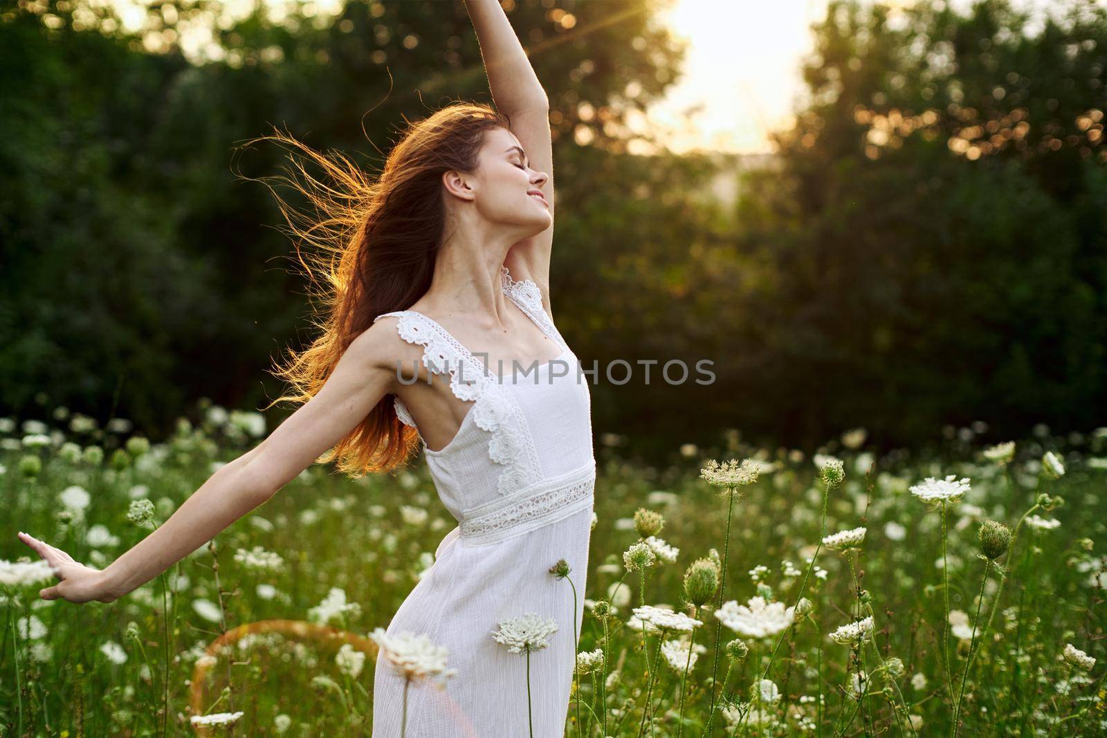 Woman in white dress in a field flowers sun nature freedom. High quality photo