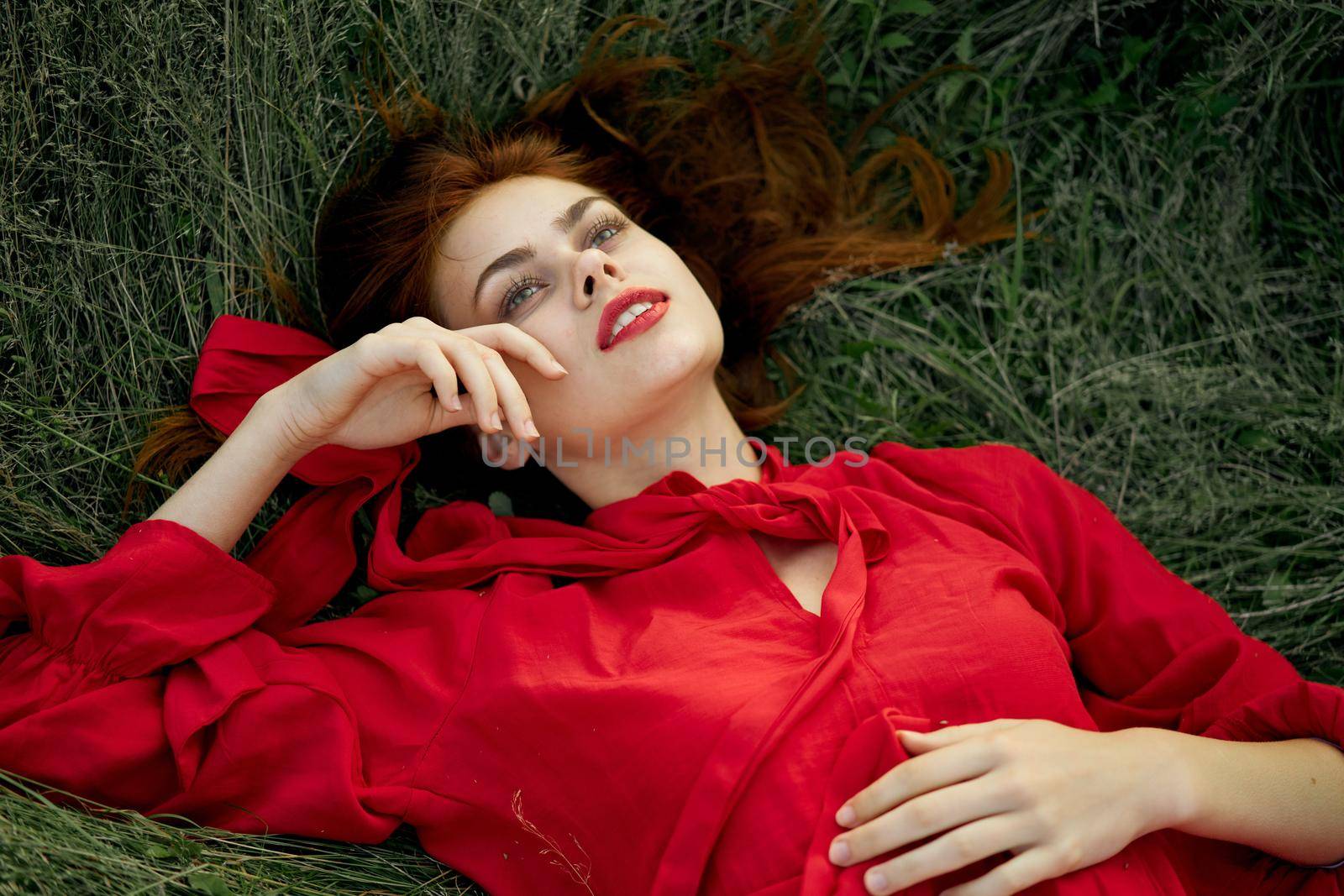 woman in red dress lies on the grass address fashion summer. High quality photo
